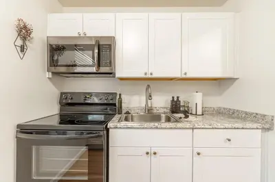 a kitchen with white cabinets and a stove and a sink at Designer Living Pet-Friendly UNR 2BR 1BA in Reno