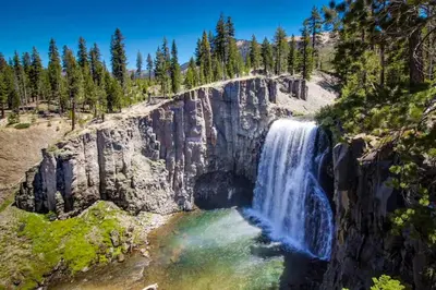 a waterfall on the side of a mountain with trees at Val D'Isere 16 in Mammoth Lakes