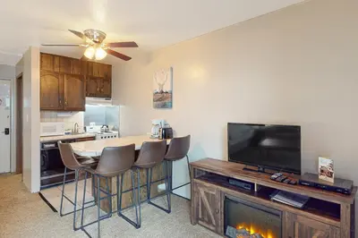 a living room with a kitchen with a table and a television at Yosemite West Condo B104 in Yosemite West