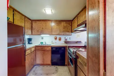 a kitchen with wooden cabinets and a sink and a refrigerator at Fireside 111 in Mammoth Lakes