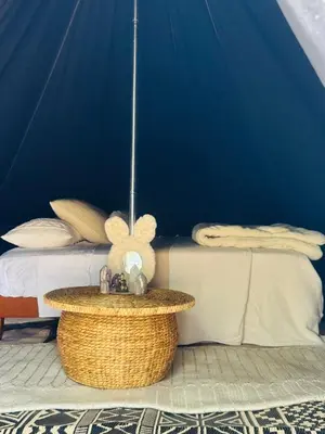 a bedroom with a blue wall and a bed and a table at Rocky Ridge Glamping Yosemite in Coarsegold