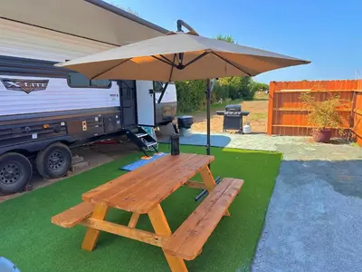 a picnic table with an umbrella next to an rv at DDs Country Camper in Reedley