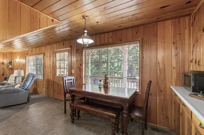 a dining room with a table in a room with wooden walls at Dogwood Star Star Location Cozy Vibes in Shaver Lake
