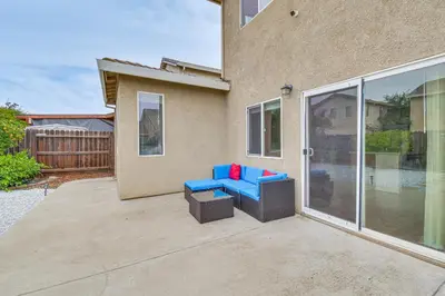 a patio with two blue chairs and a table at 7 Mi to Lake Yosemite Family Home with Fenced Yard in Merced