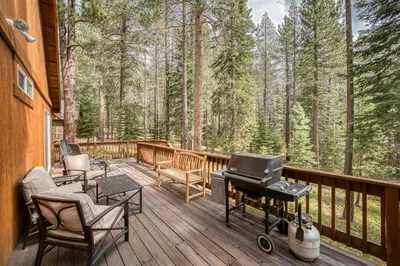 a screened in porch with a grill on a deck with trees at Scarlet Hollow Cabin at Tahoe Donner by Tahoe Getaways - 3BR w HOA Amenities in Truckee
