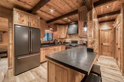 a kitchen with wooden cabinets and a stainless steel refrigerator at Songbird Cabin at Chambers by Tahoe Getaways - Pet-Friendly 2 BR with HOA Access in Homewood