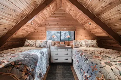 a bedroom with two beds in a log cabin at Songbird Cabin at Chambers by Tahoe Getaways - Pet-Friendly 2 BR with HOA Access in Homewood