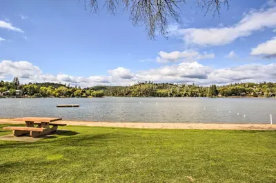 a picnic table in the grass next to a lake at Game Room and Bar Wooded Pine Mountain Lake Retreat in Groveland