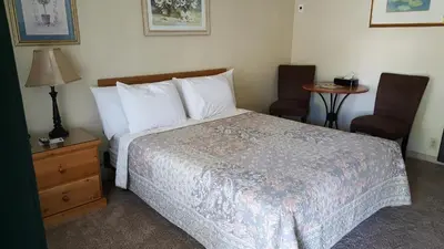 a bedroom with a bed and two chairs and a table at Bishop Village Motel in Bishop