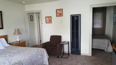 a bedroom with a bed and a chair and a window at Bishop Village Motel in Bishop
