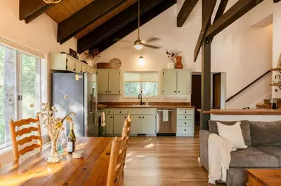 a kitchen and living room with a table and a couch at Tallwood Cabin A Treetop Mountain Retreat in Shaver Lake