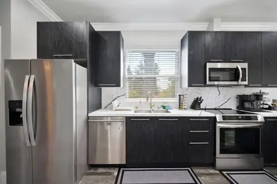 a kitchen with stainless steel appliances and black cabinets at Walk to UC Davis Medical Center! Duplex with Patio in Sacramento