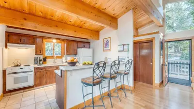 a kitchen with wooden cabinets and a counter with stools at Sleeps 20 2 Homes Near Ski Resort Beach Lake Access Pool Homewood in Tahoma