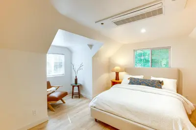 a white bedroom with a bed and a chair at Hot Tub and Game Room Luxe Cabin, Day Trip to Tahoe in Pollock Pines