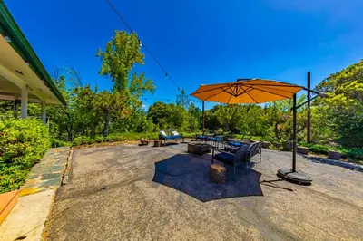 a patio with a table and an umbrella at Sierra View Retreat with Newly Installed Hot tub! in Oakhurst