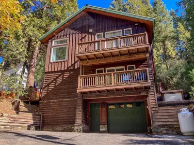a log cabin with a balcony and a garage at Boom Chalet Yosemite in Oakhurst