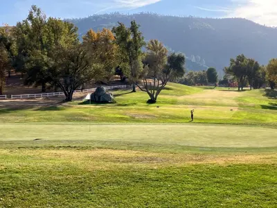 a golf course with a man on a green at Boom Chalet Yosemite in Oakhurst