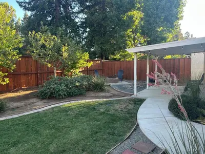 a backyard with a wooden fence and a garden at Contemporary, newly renovated and great location in Fresno