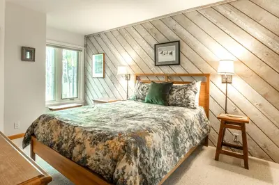a bedroom with a large bed with a wooden wall at 3 Bedrooms + Loft townhome in Snowcreek Phase 3, Private Pool Table Sleeps 6 Guests, Dog Friendly in Mammoth Lakes