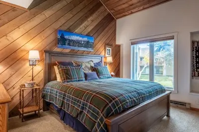 a bedroom with a bed and a wooden wall at 3 Bedrooms + Loft townhome in Snowcreek Phase 3, Private Pool Table Sleeps 6 Guests, Dog Friendly in Mammoth Lakes