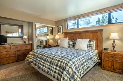 a bedroom with a bed and a tv and windows at Updated1849 Townhome #611, Steps to Canyon Lodge 4 Bed/3BA, hot tubs, game rm, sauna! in Mammoth Lakes