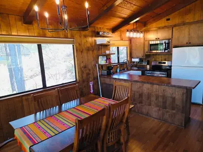 a dining room with a table and a kitchen at Lakeview Yosemite 3B2b Private House - Panoramic Sauna - Seasonal Hot Tub Jacuzzi in Groveland