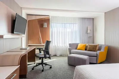 a hotel room with a bed and a desk and a chair at Courtyard by Marriott Fresno Downtown in Fresno