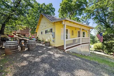 a yellow tiny house with a porch and a flag at Cozy Mountain Cabin Yosemite Dodge Ridge Ski in Tuolumne