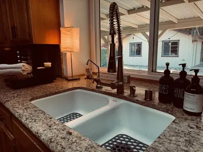 a kitchen sink with bottles of wine on a counter at Magic Sequoia Spacious Home in Three Rivers