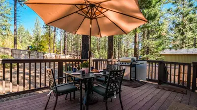 a table and chairs on a deck with an umbrella at Steps to Trails Minutes to Heavenly Fireplace Deck BBQ Bluewood Cabin by AvantStay in South Lake Tahoe