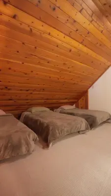 two beds in a room with a wooden ceiling at Little Bear Lodge in Springville