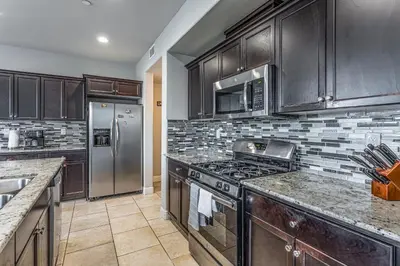 a kitchen with wooden cabinets and a stainless steel refrigerator at Nic's Home in Visalia