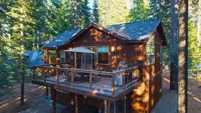 a cabin in the woods with a large deck at Cozy Tahoe Retreat w Hot Tub Movie Room Forest Views 10th ave 2 by AvantStay in Tahoma