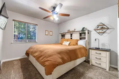 a bedroom with a bed and a ceiling fan at Halonas Cozy Cabin 2M To Lake in Shaver Lake
