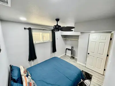 a bedroom with a blue bed and a ceiling fan at Halonas Cozy Cabin 2M To Lake in Shaver Lake