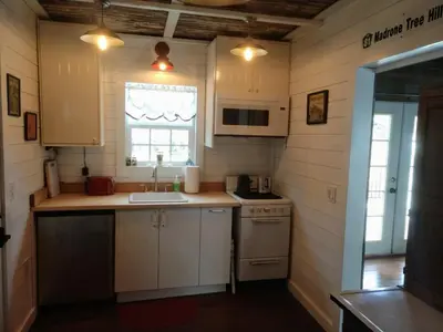 a kitchen with white cabinets and a sink and a window at Meadow Creek Cabin in Camino