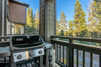a grill on a balcony with a view of a river at Mammoth Green #220 - Nearly Ski-In Ski-Out 3 Bedroom 2 Bath, Sleeps 8 in Mammoth Lakes