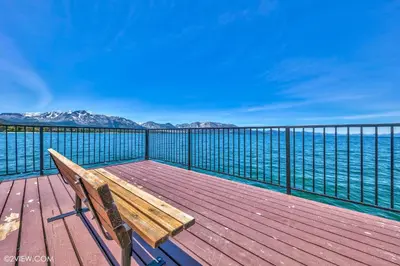 a wooden bench sitting on a deck overlooking the water at Tahoe Keys Studio Condo in South Lake Tahoe