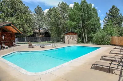 a swimming pool with chairs and a house at Chateau Blanc #2 condo in Mammoth Lakes