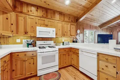 a kitchen with white appliances and wooden cabinets at Tahoe Getaway in Homewood