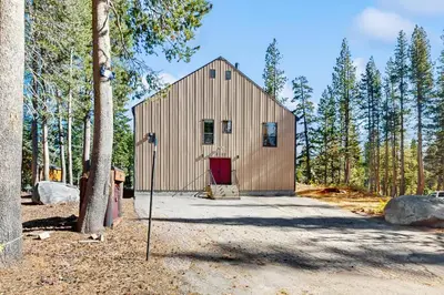 a barn with a red door in the woods at Serene Road Lodge in Soda Springs