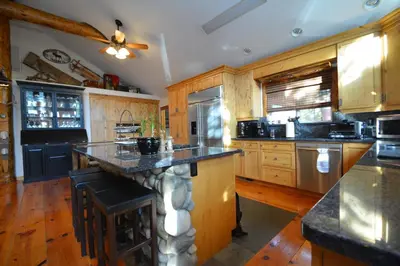 a large kitchen with wooden cabinets and a large island at Owens Den- Lake AreaFree Night Special in Bass Lake