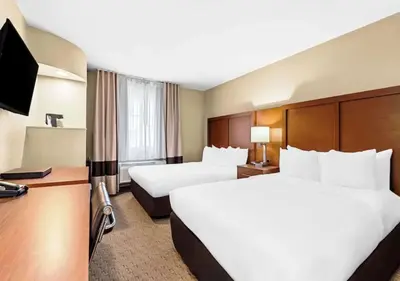 a hotel room with two beds and a flat screen tv at Aurora Inn in Modesto
