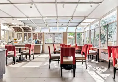 a restaurant with red chairs and tables and windows at Aurora Inn in Modesto