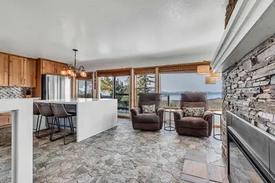 a kitchen with a stone wall and chairs and a counter at Wooded Hilltop Stay Shared Hot Tub + Lake Views in Stateline