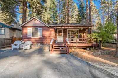 a cabin in the woods with a porch and chairs at Diana's Cabin by Tahoe Getaways - Pet-Friendly 2BR in Kings Beach w Backyard & Walk to Lake! in Tahoe Vista