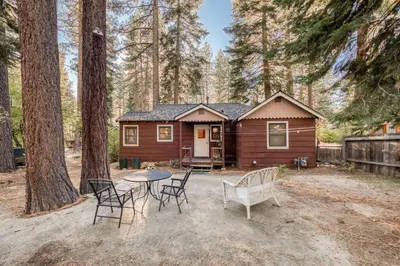 a cabin in the woods with a table and chairs at Diana's Cabin by Tahoe Getaways - Pet-Friendly 2BR in Kings Beach w Backyard & Walk to Lake! in Tahoe Vista