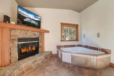 a bath tub in a room with a fireplace at Knotty by Nature 3 bed home in South Lake Tahoe