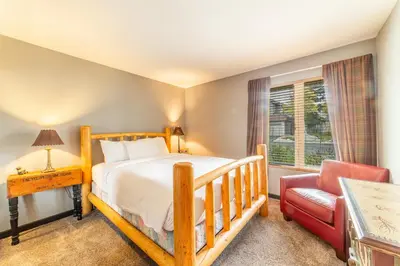 a bedroom with a wooden bed and a red chair at Tranquil & Woodsy 2/2 Retreat – Jacuzzi, W/D, BBQ! in Mammoth Lakes