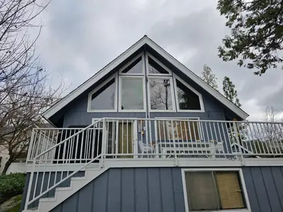 a blue house with a porch and a balcony at Lakeview Lodge, bookable boat slip! in Bass Lake